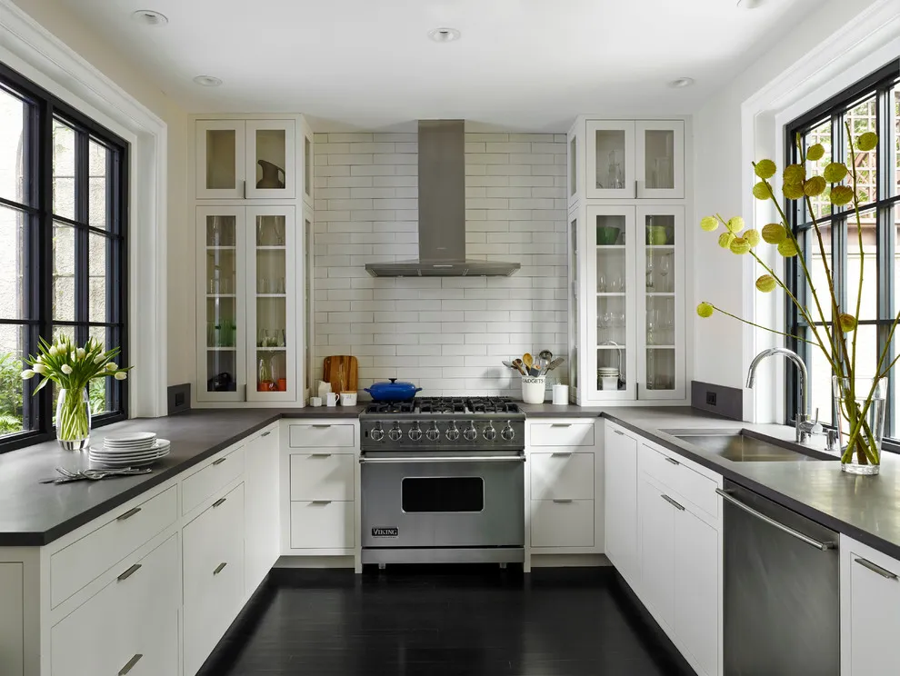 White cabinets sit beneath dark counters beside black-framed windows